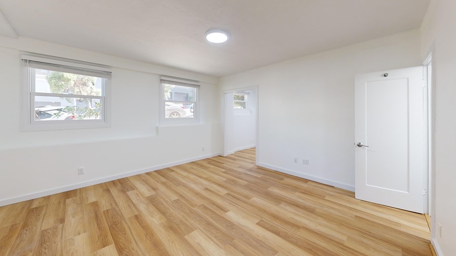 A room with wooden flooring and white walls.